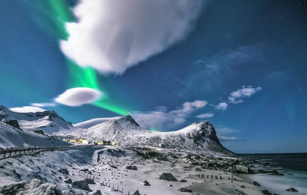 Aurores boréales illuminant un paysage enneigé en Norvège.